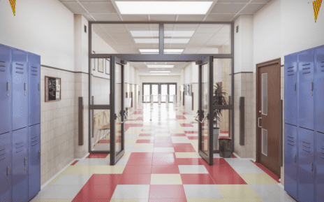 Image of a school hallways with red and white checkered floors, white walls, blue lockers and glass doors with black trim.